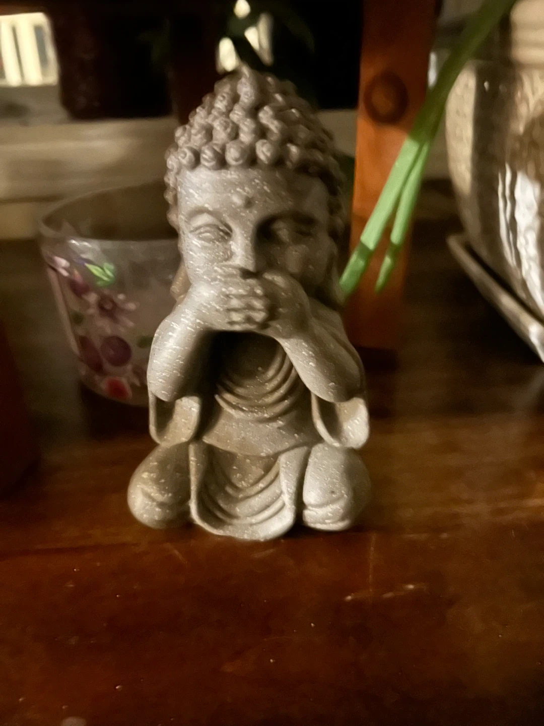 Stone-look Buddha statue, hands covering mouth