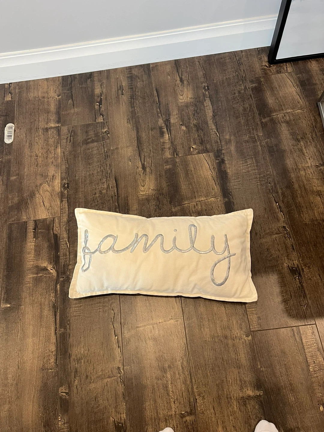 Cream coloured throw pillow with 'family' embroidered in silver