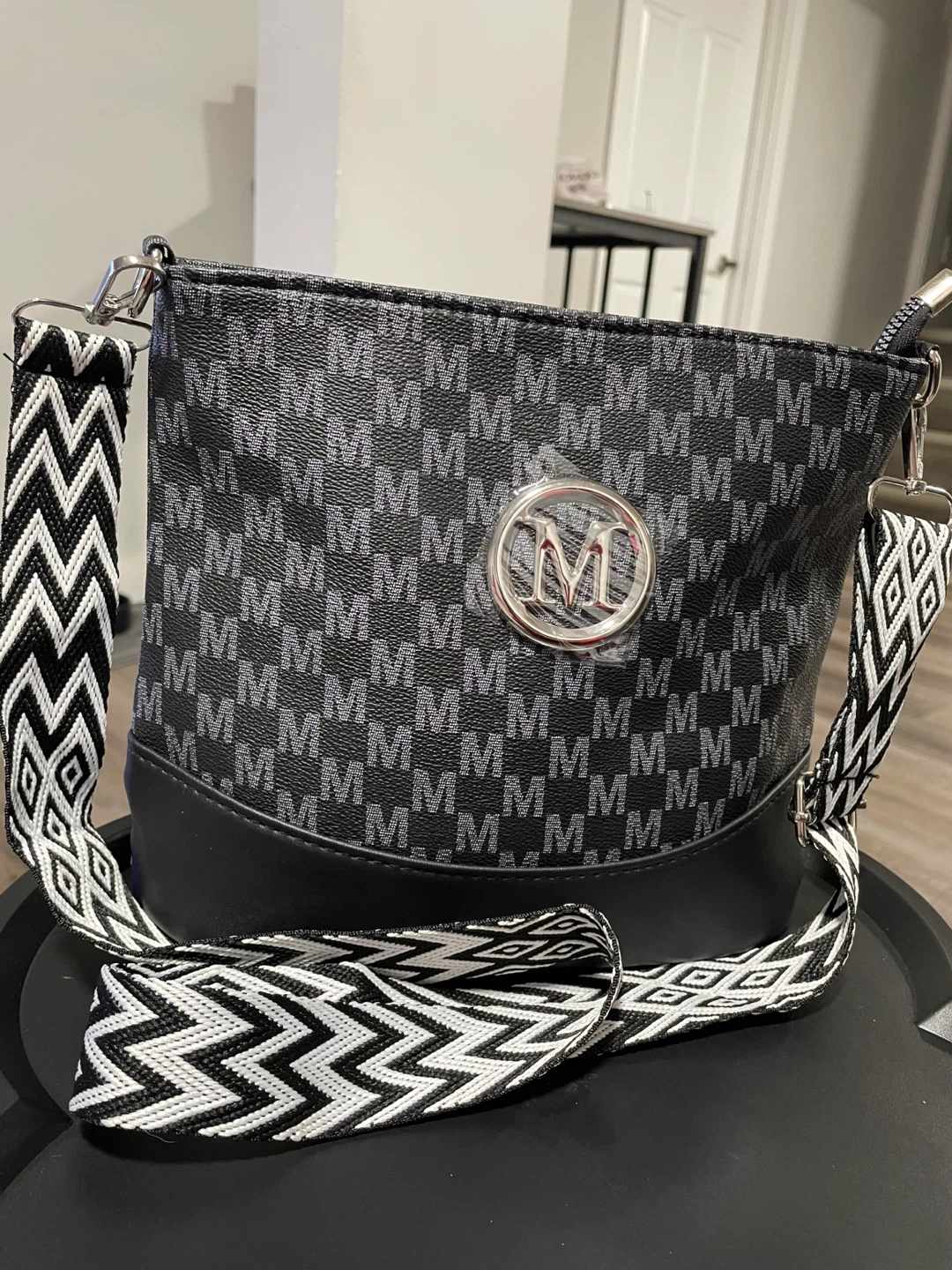 Black crossbody shoulder bag with 'M' pattern
