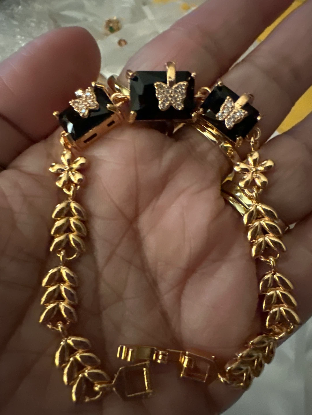 Gold tone bracelet with black square gems and butterfly accents