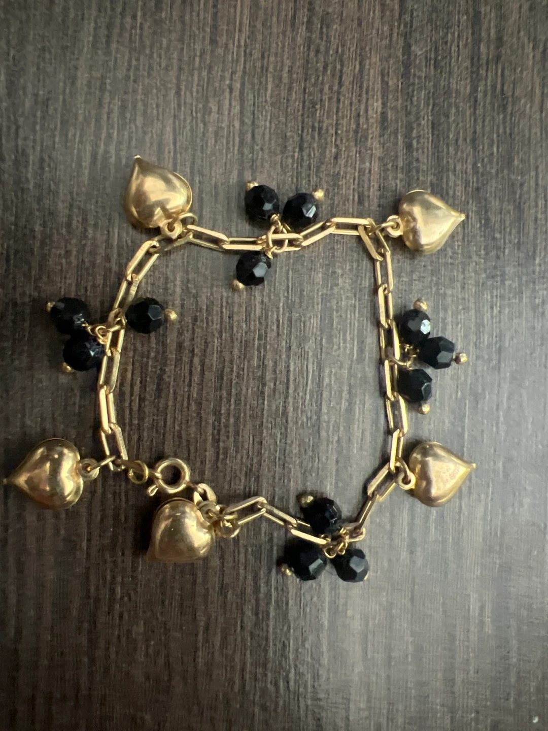 Gold tone bracelet with black beads and heart charms