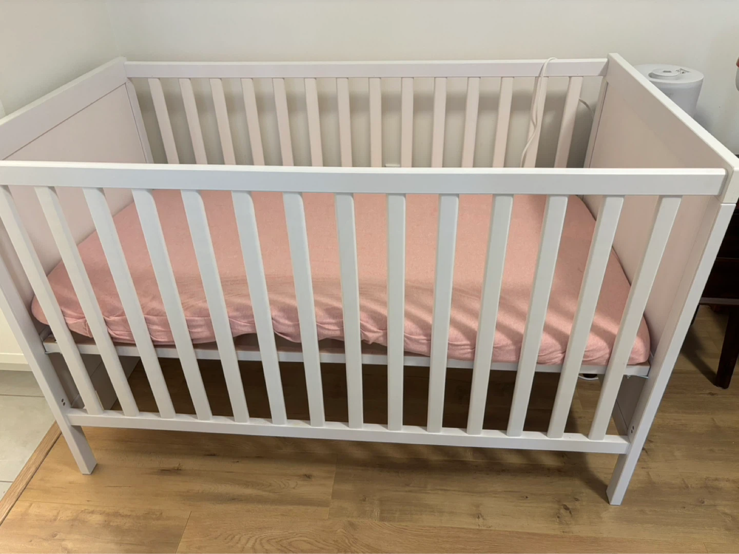 White Baby Crib with Pink Sheet