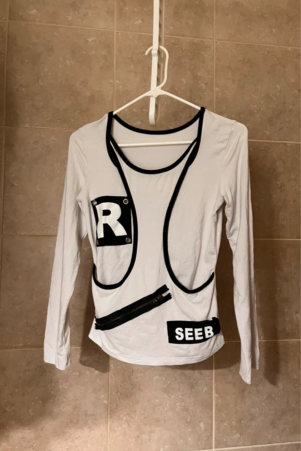 White long-sleeve top with black trim and decorative zipper