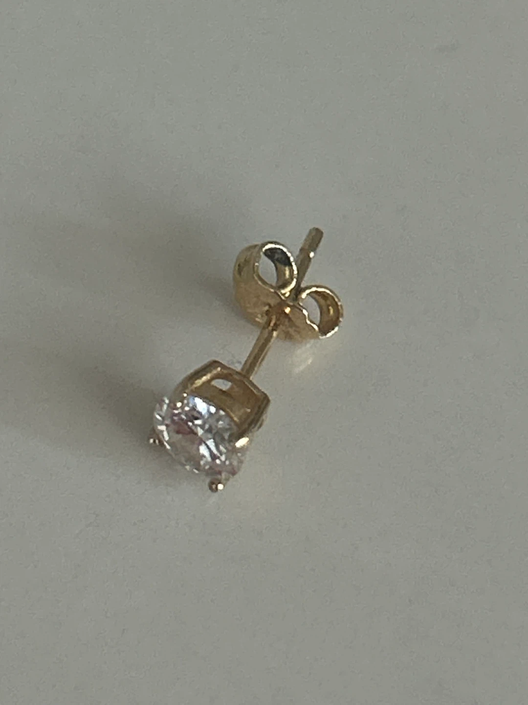 One Gold-tone stud earring with clear stone stamp 925