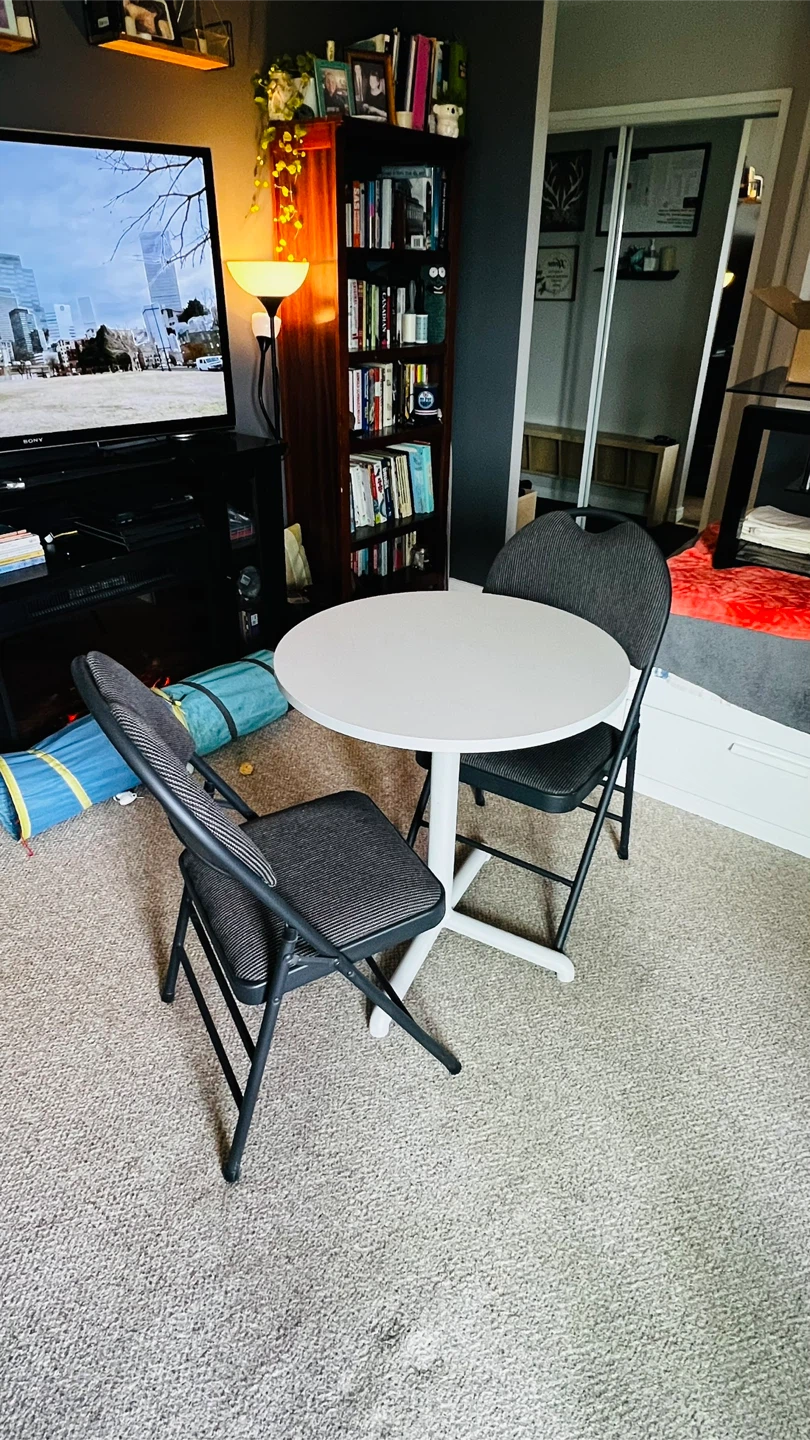 Grey round table and two folding chairs