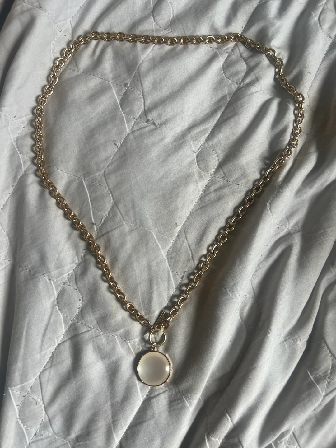 Gold tone necklace with white pendant