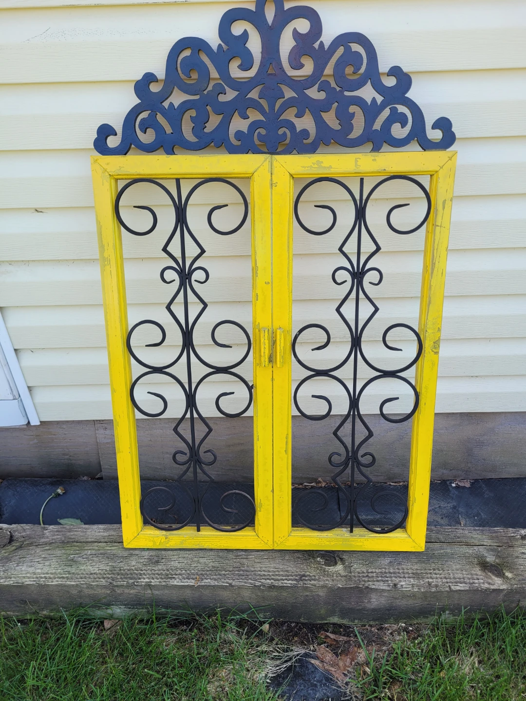 Yellow Decorative Window Frame with Black Metal Scrollwork