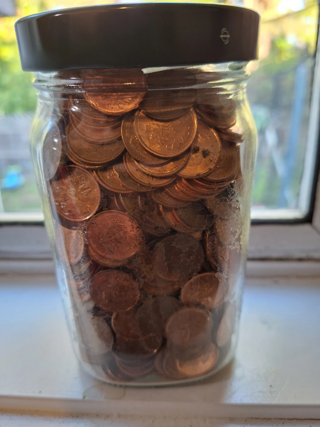 Glass pickle jar full of pennies