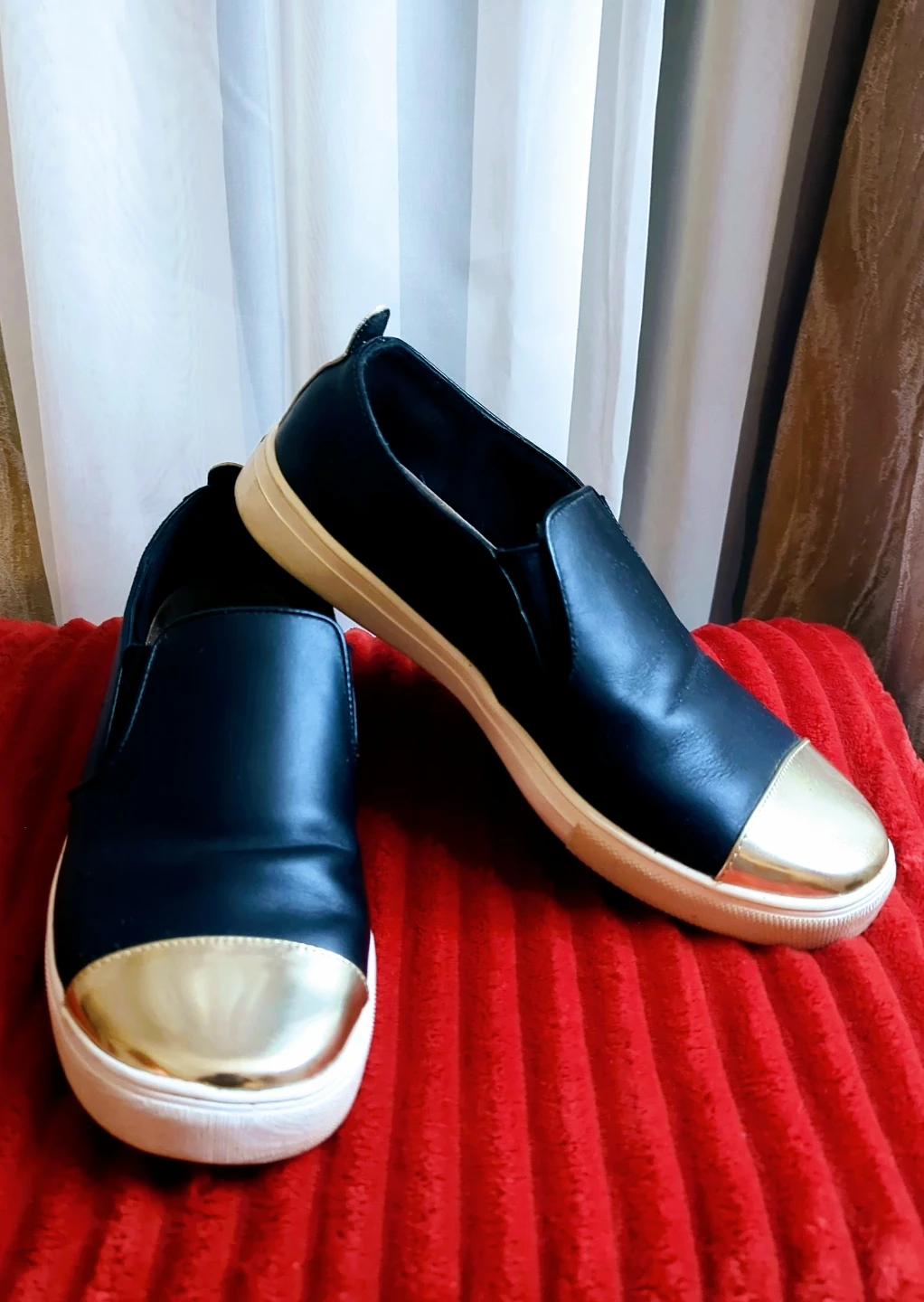 Black slip-on sneakers with gold cap toe