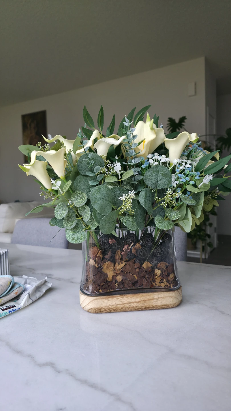 Faux floral arrangement in glass vase with wood base