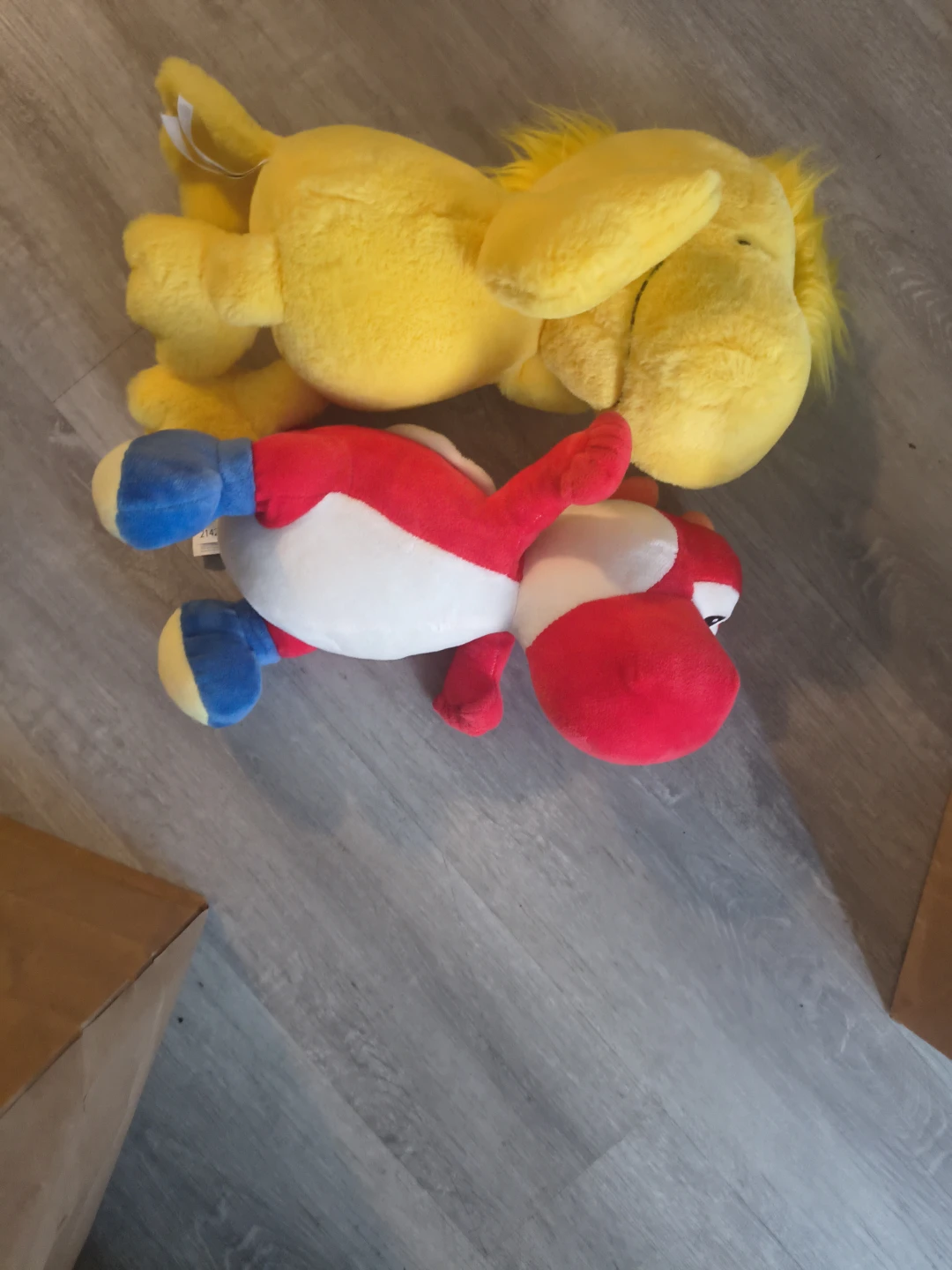 Two plush toys: yellow character and red Yoshi