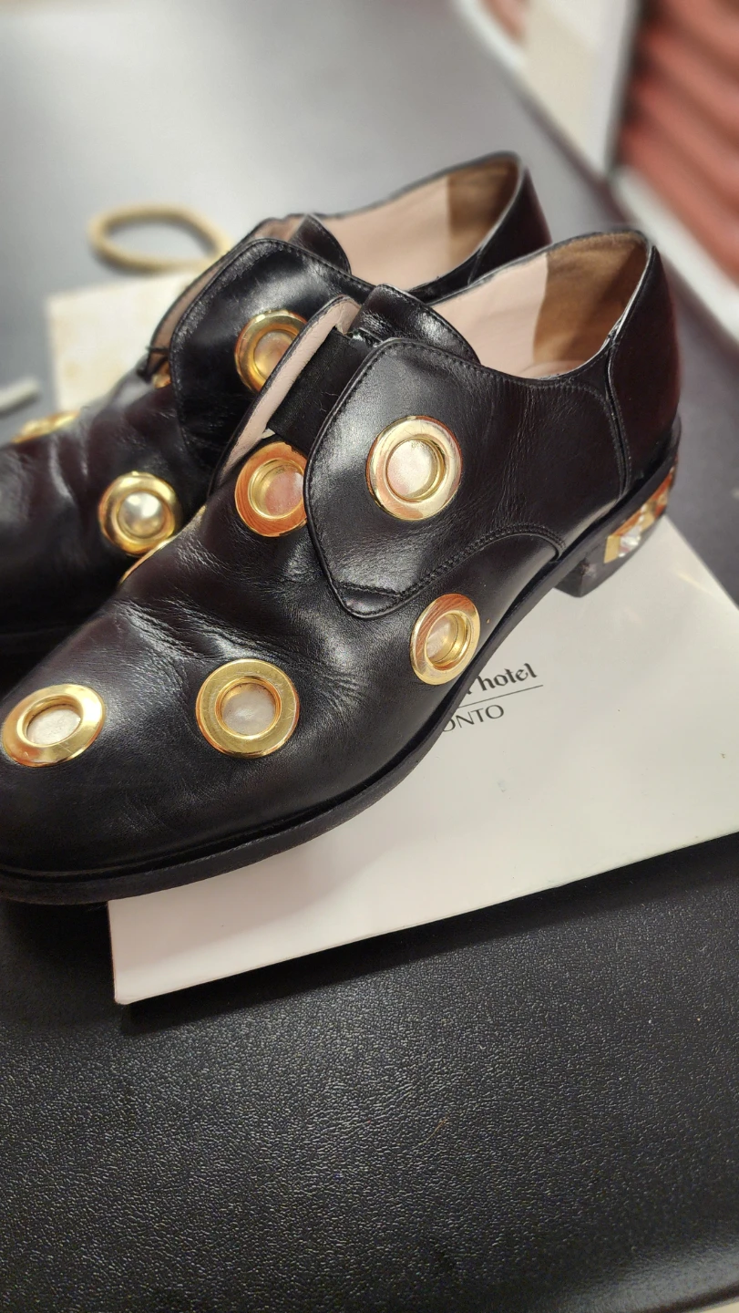 Black leather loafers with gold eyelets