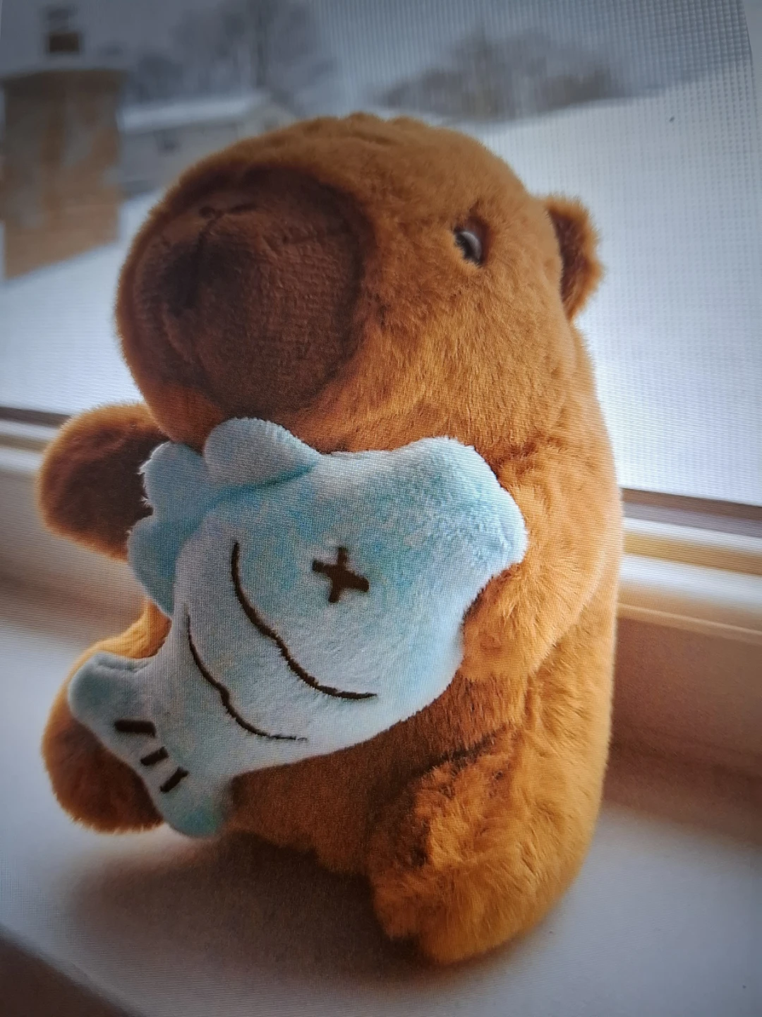 Brown bear plush holding blue fish toy