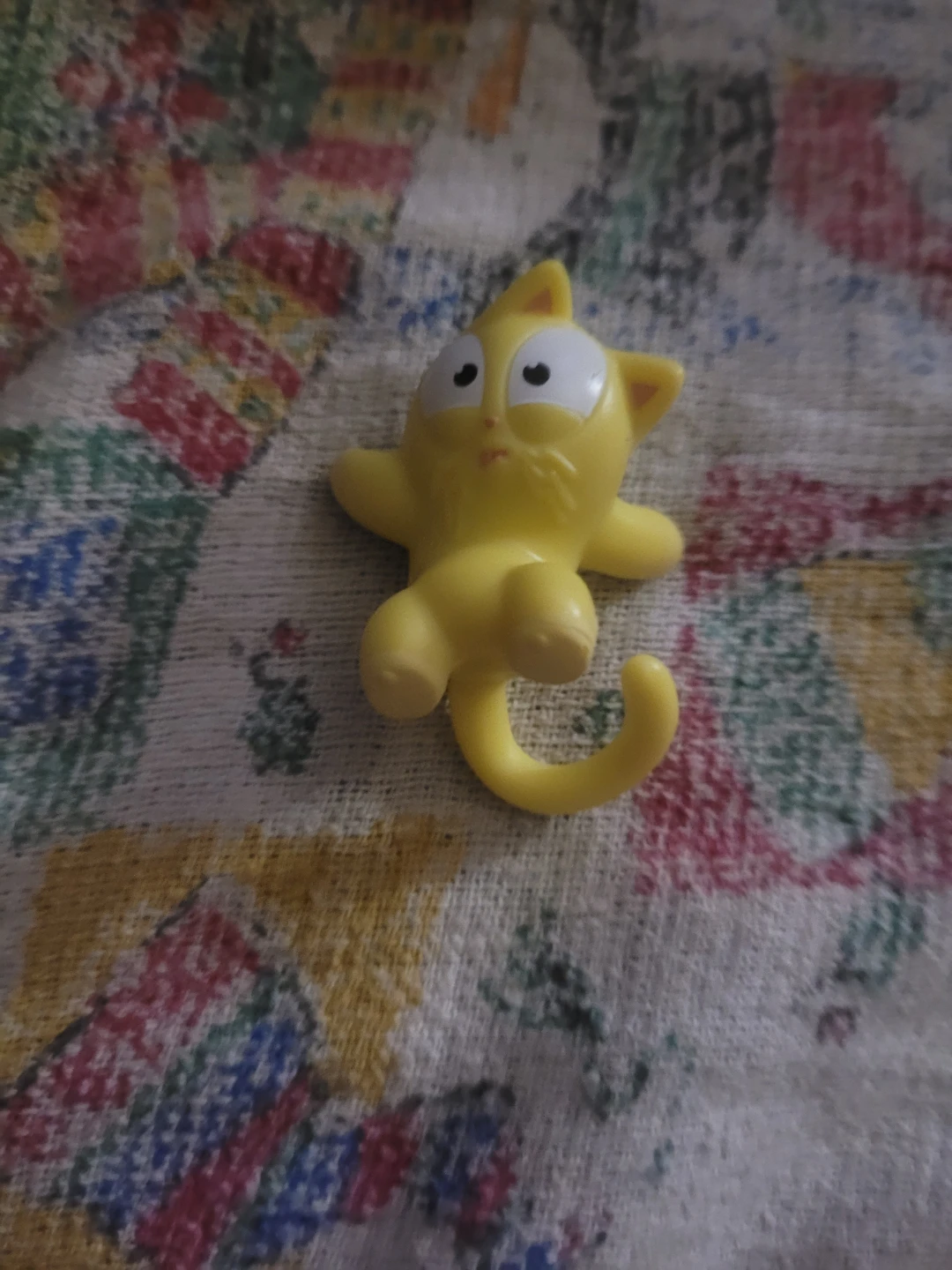 small, yellow plastic cat figurine, possibly from the Hasbro