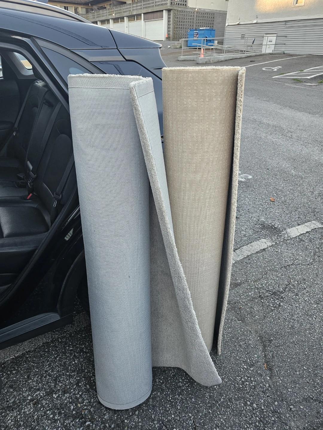 Two rolled carpets, grey and beige