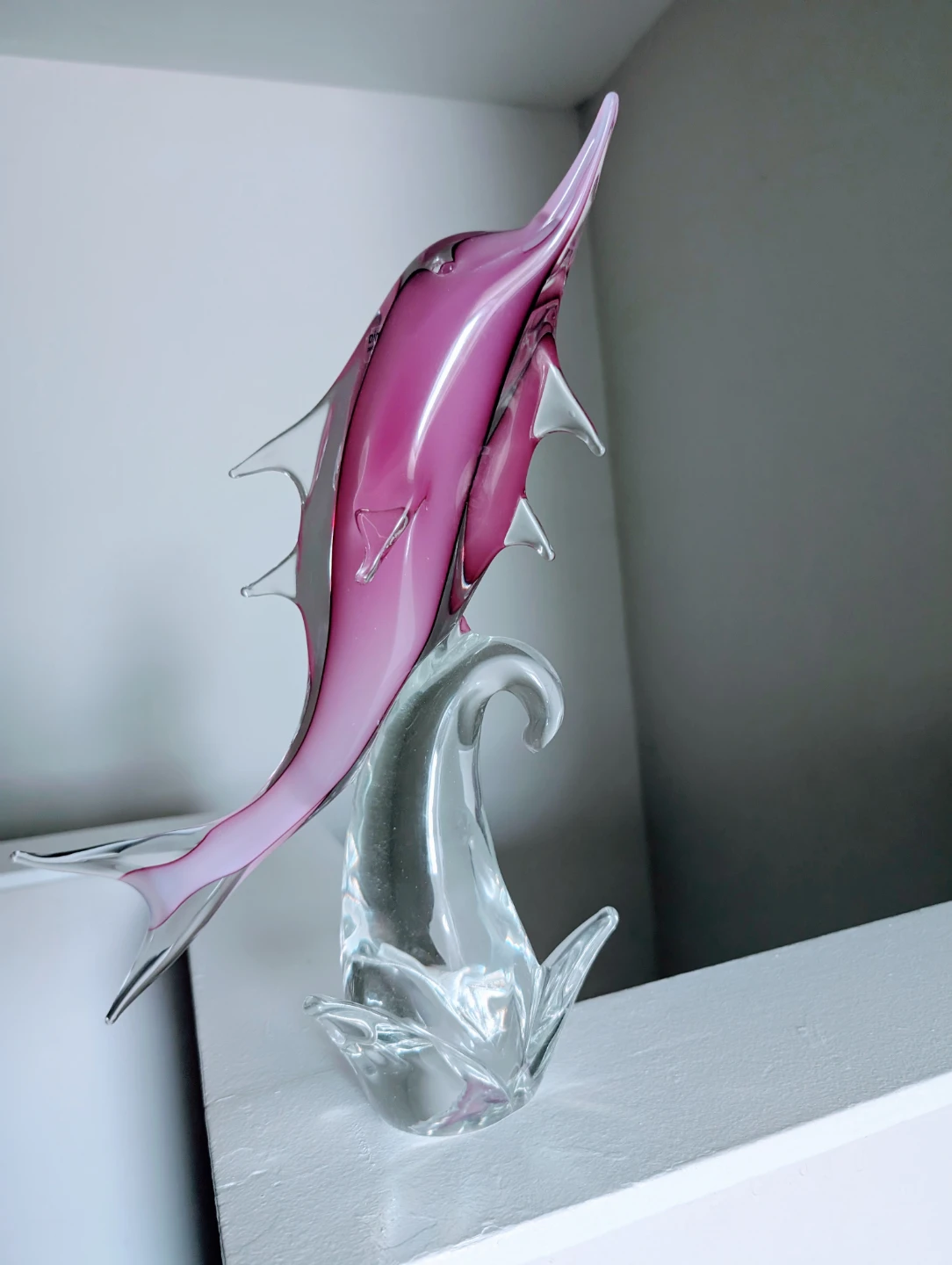Pink glass dolphin figurine on clear base