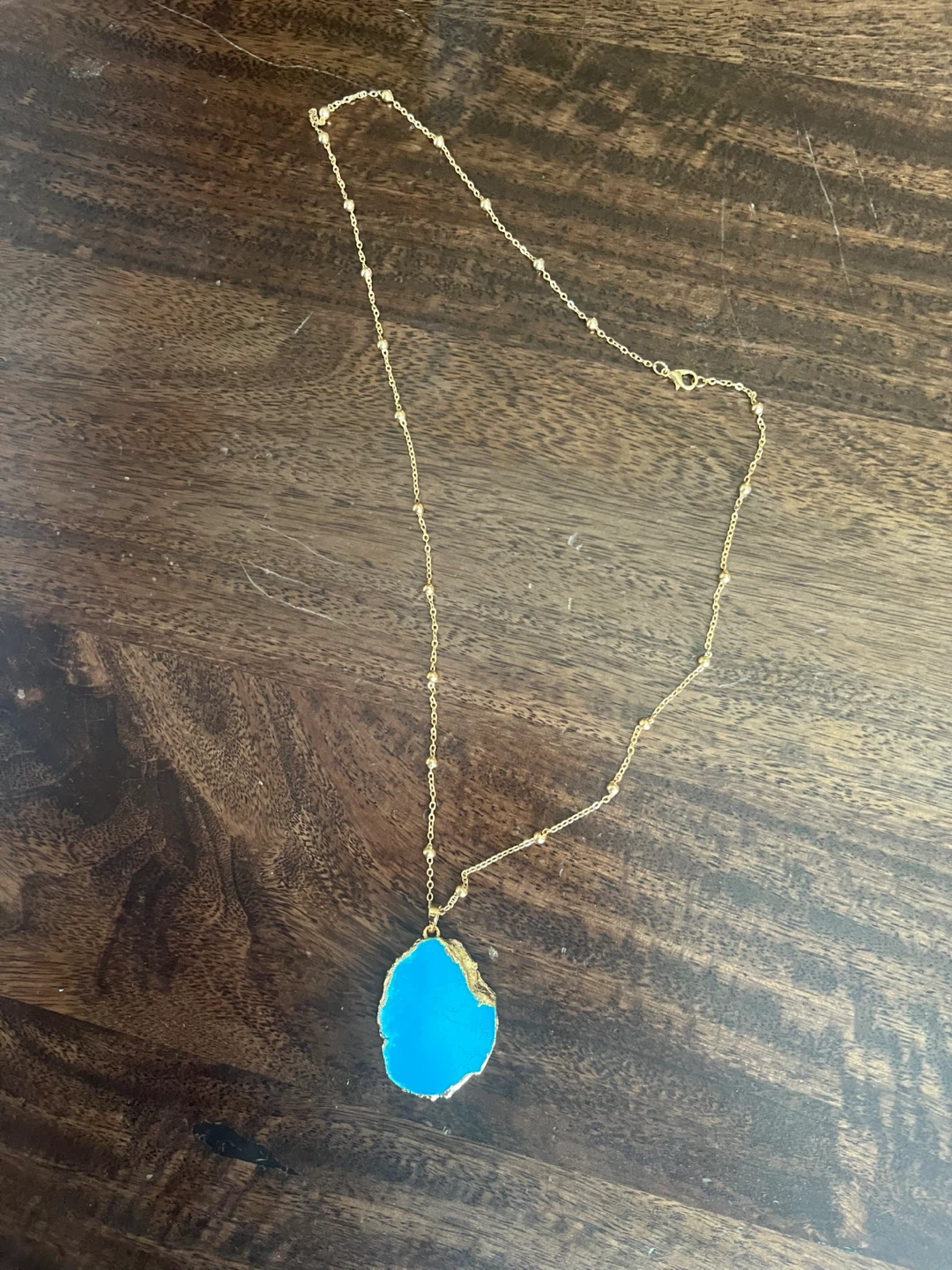 Gold tone necklace with blue stone pendant