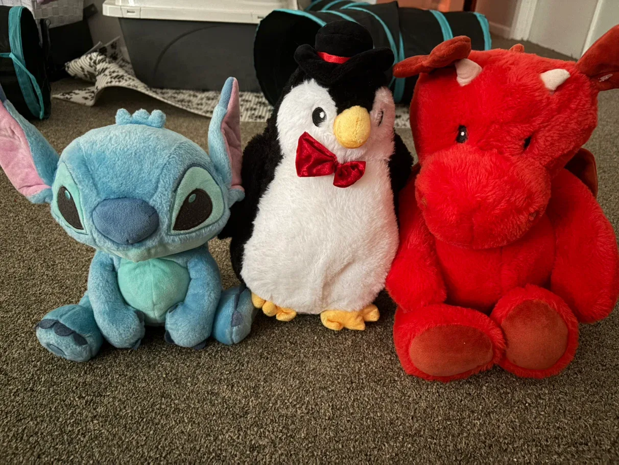 Three stuffed animals: Stitch, Penguin, Red Dragon