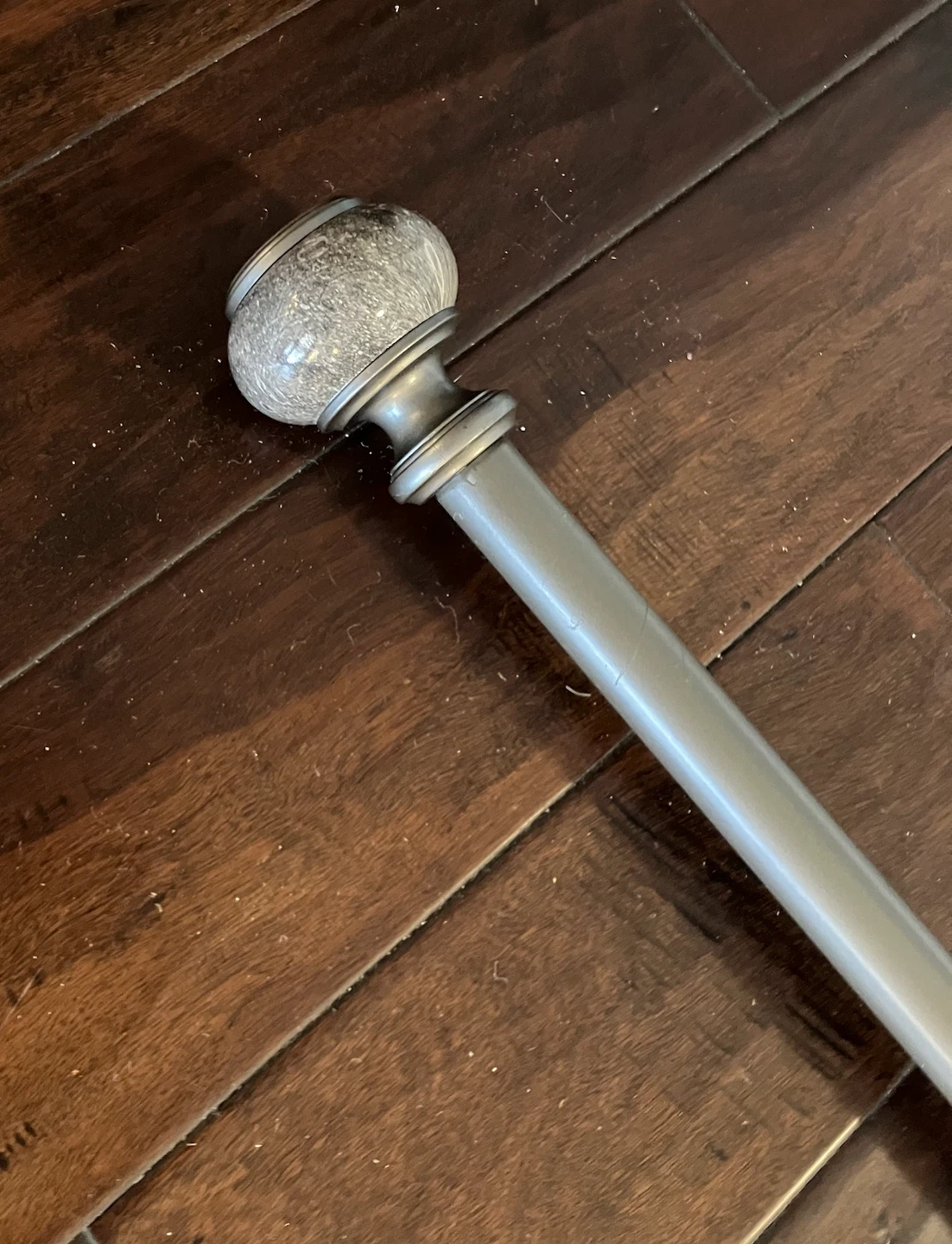 Grey metal curtain rod, extendable 4’ to 10’.