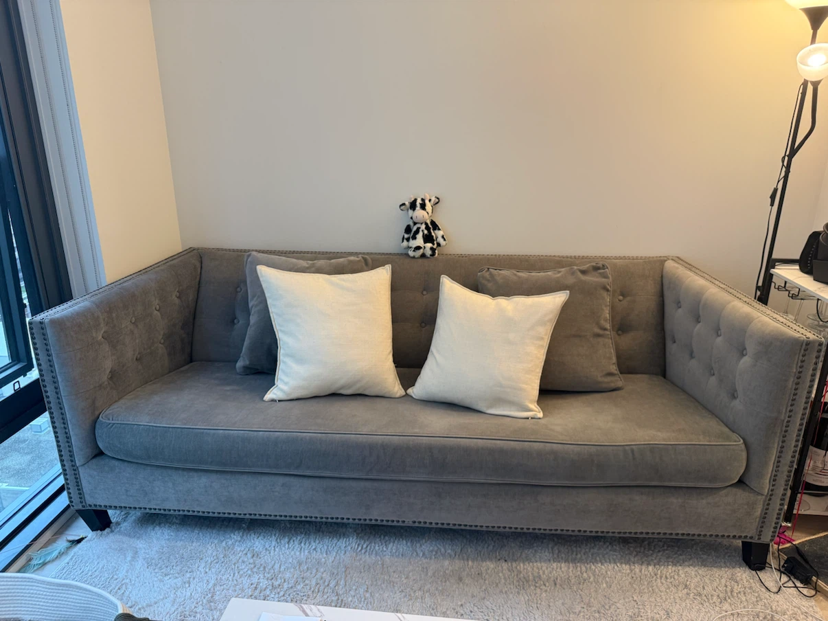 Grey tufted couch with 2 accent pillows