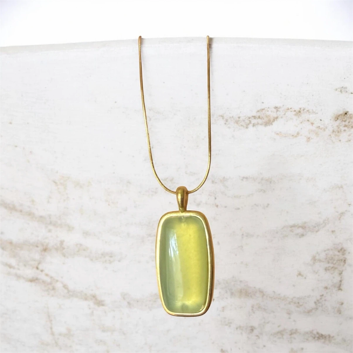 Gold tone necklace with a rectangular pale green pendant