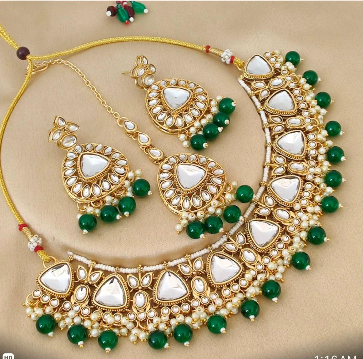 Gold coloured necklace set with green beads and white stones