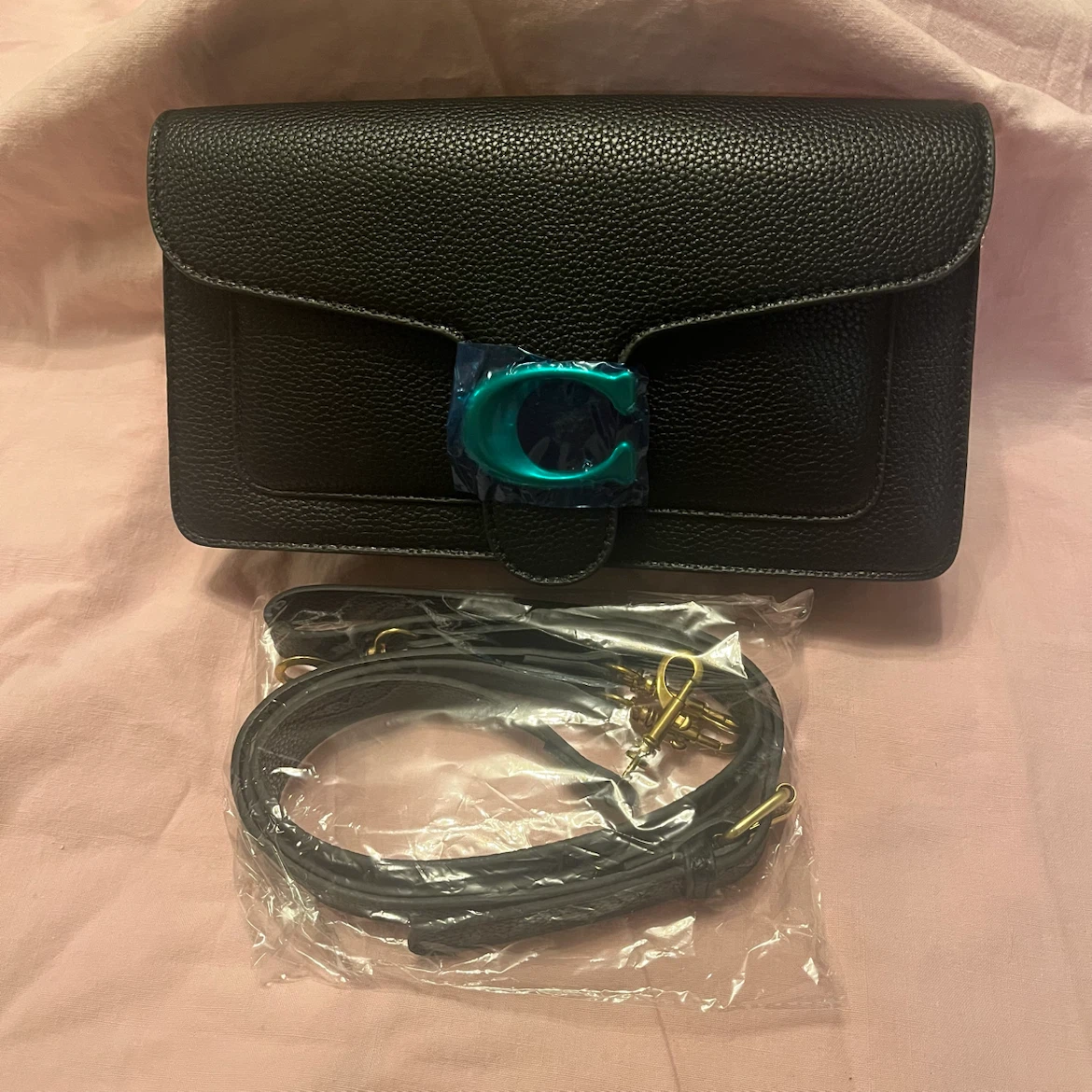 Black pebbled leather crossbody bag with teal "C" logo