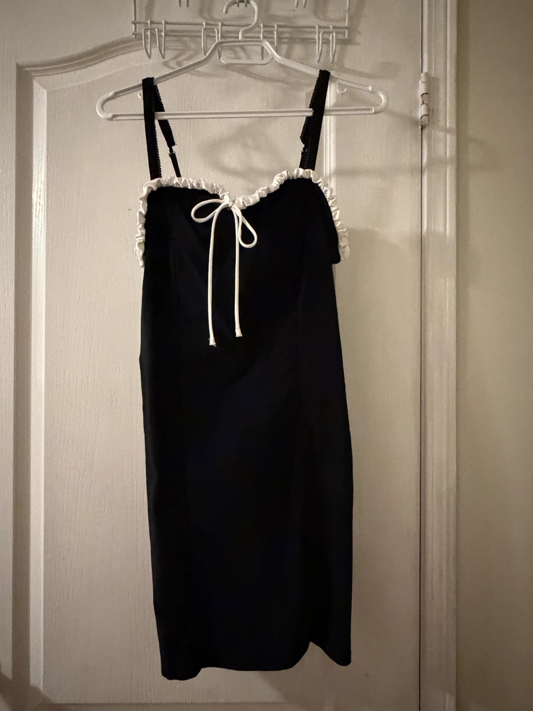 Black dress with adjustable straps and a white ruffle trim