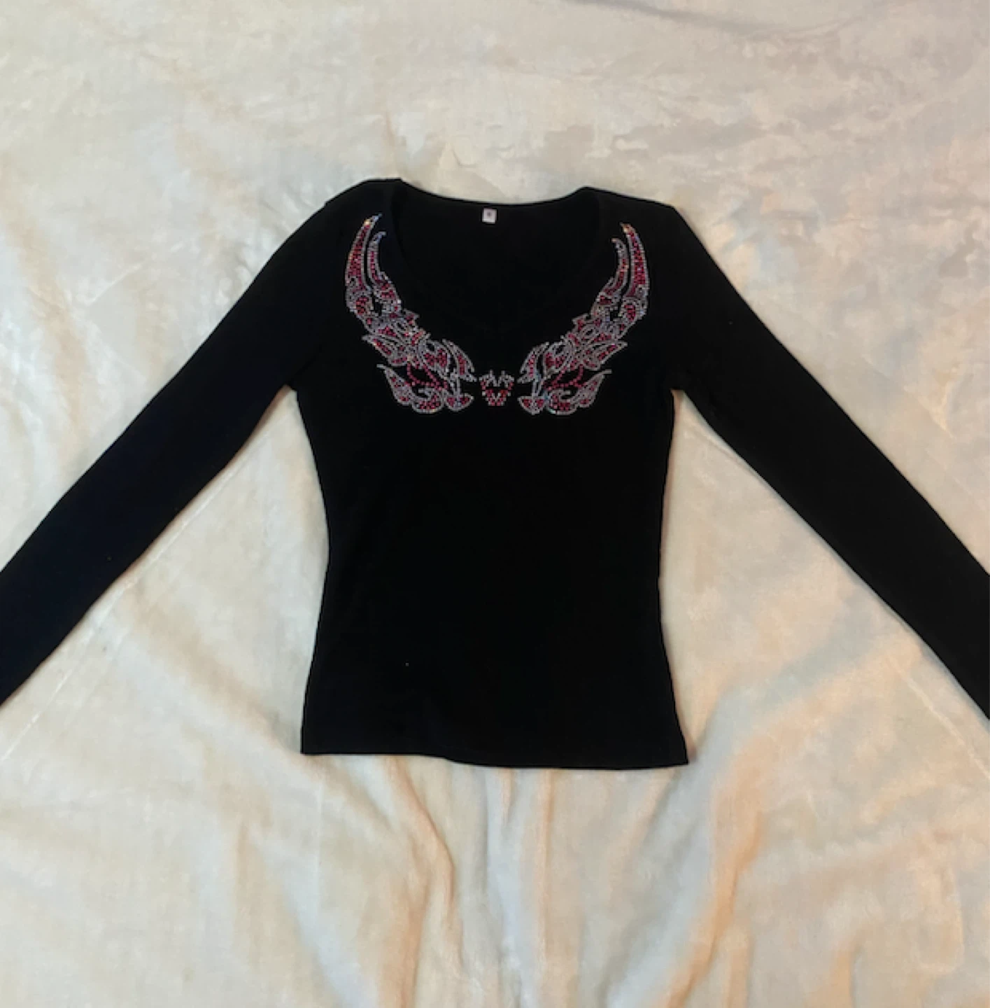 Black long-sleeve top with rhinestone wing design