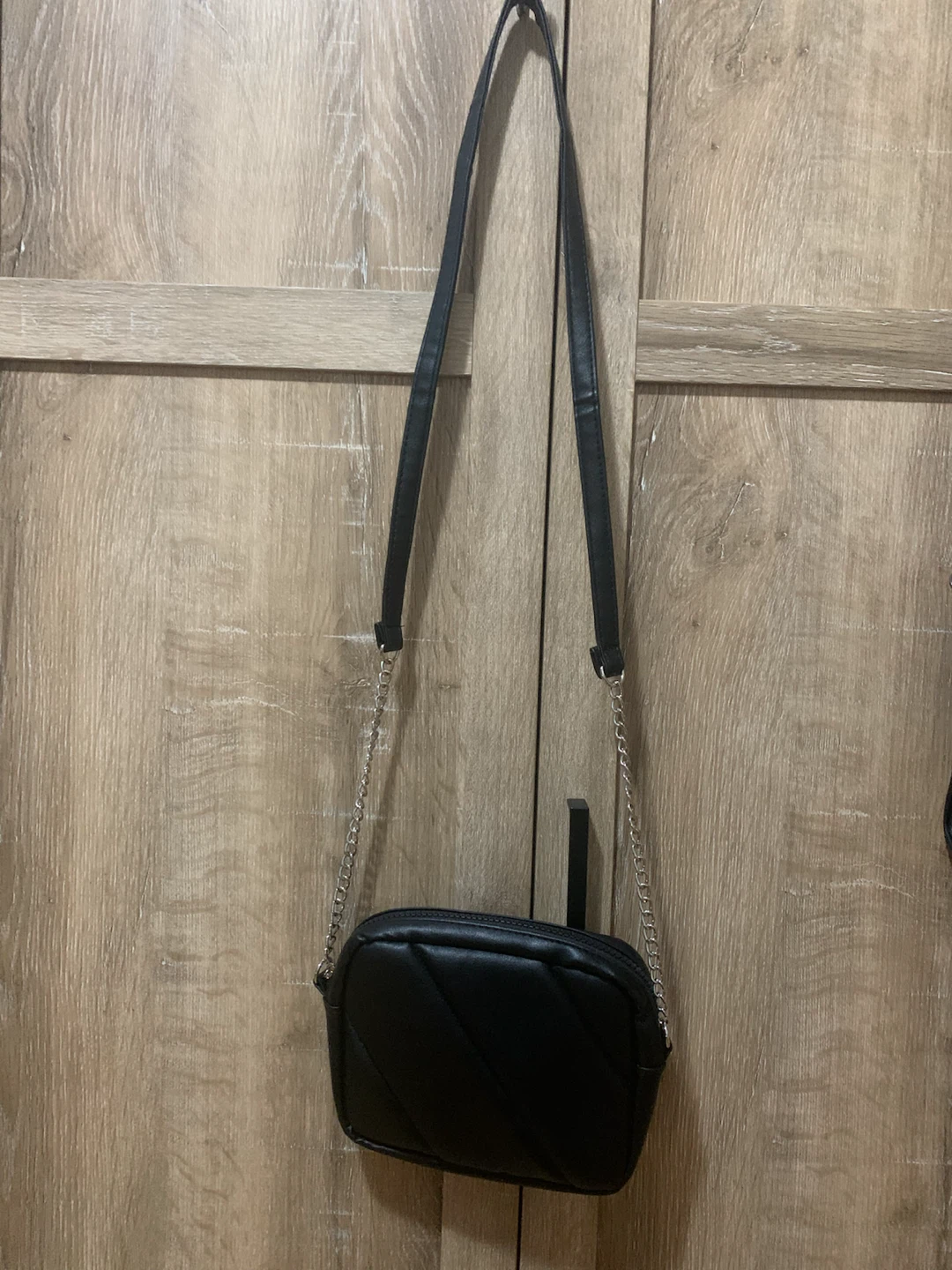 Black quilted crossbody bag with silver chain strap