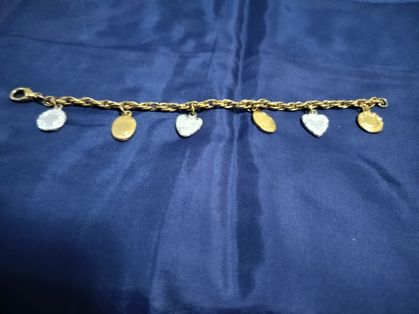 Gold tone charm bracelet with oval and heart charms