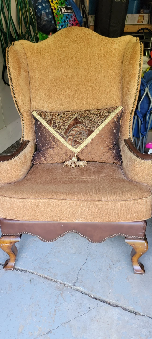 Brown Upholstered Wingback Armchair with Decorative Pillow