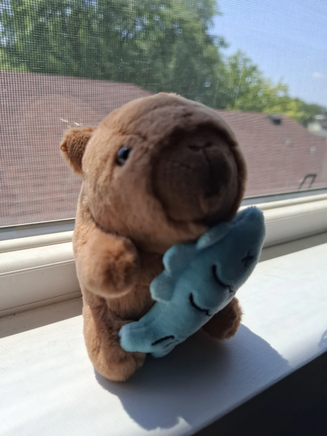Capybara plush holding blue fish keychain
