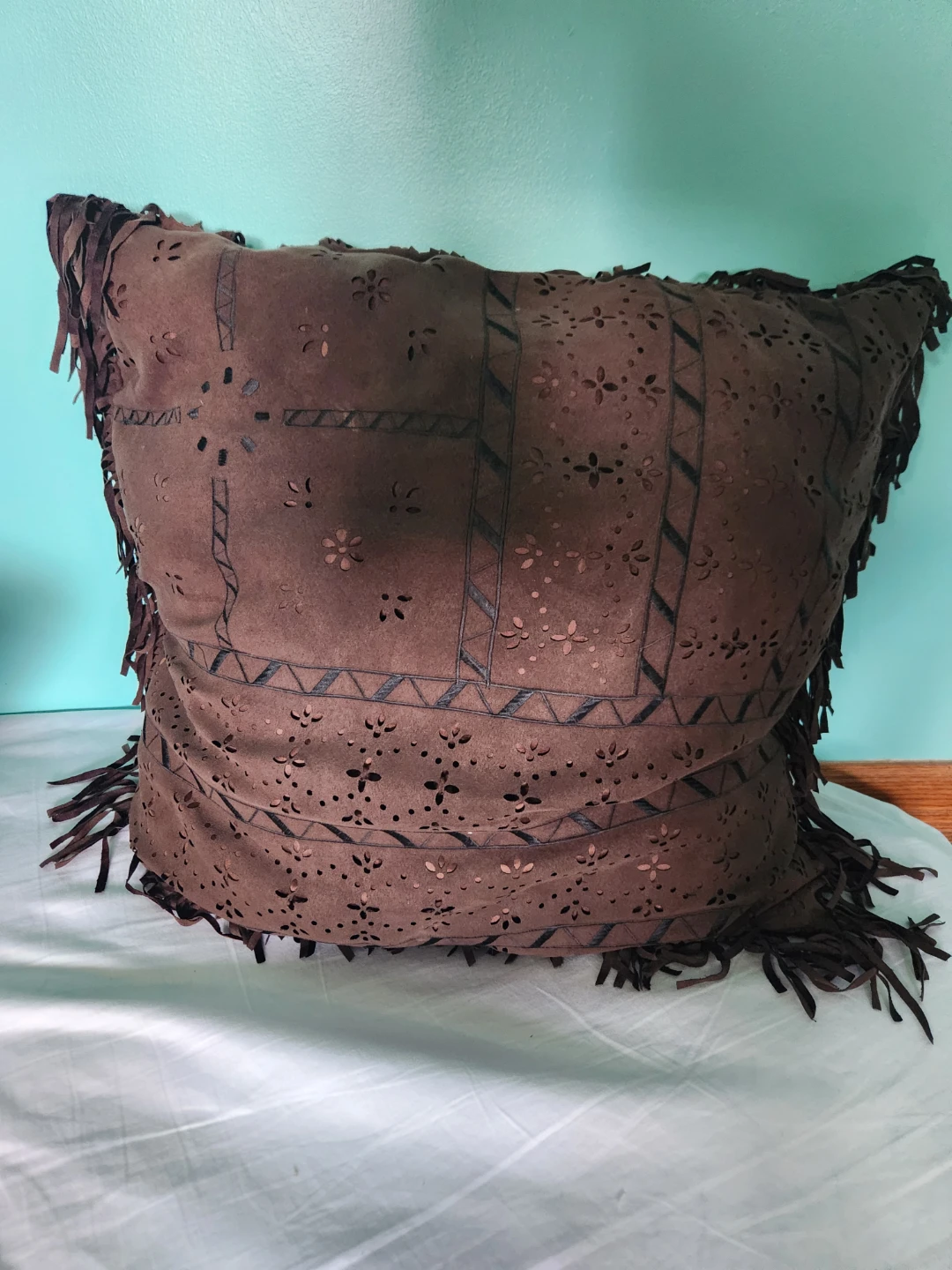 Brown decorative pillow with fringe and cutouts