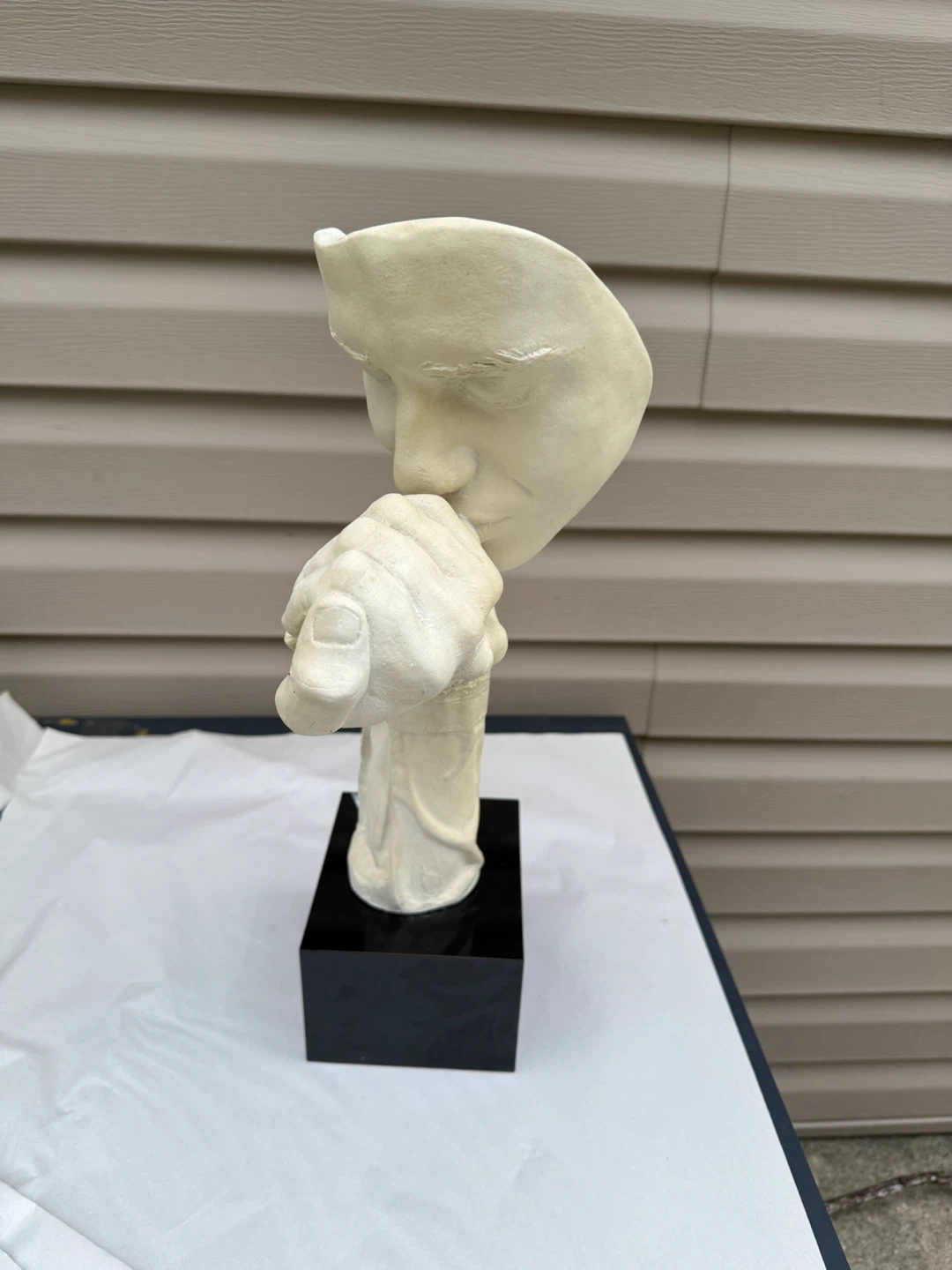 Sculpture of a face with hand over mouth