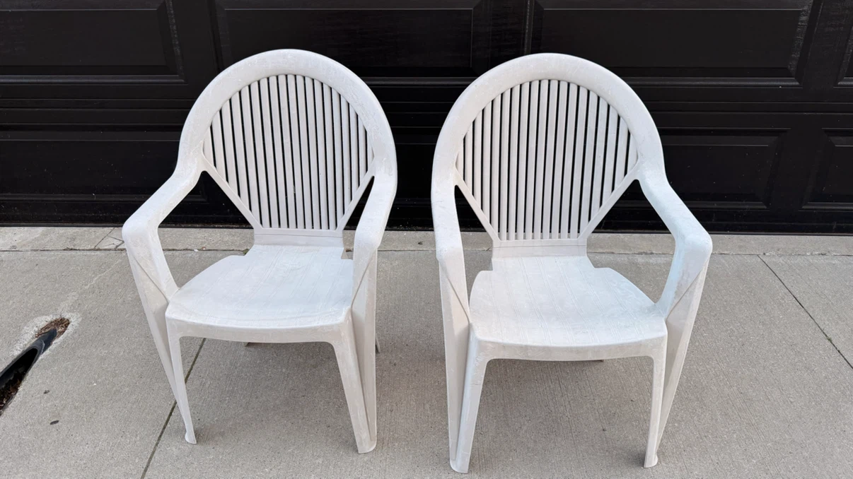 Two white plastic patio chairs