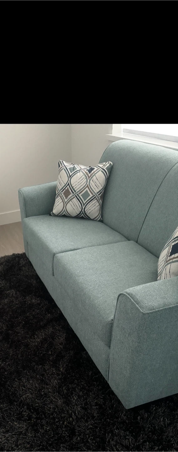 Teal upholstered sofa with decorative pillows