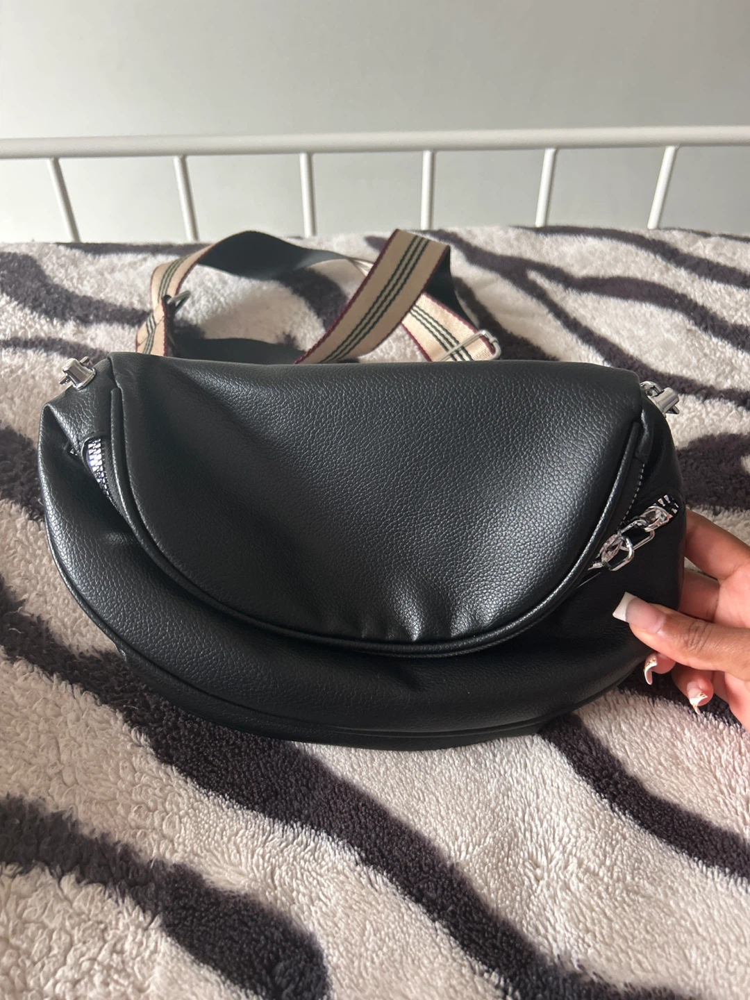 Black crescent crossbody bag with striped strap