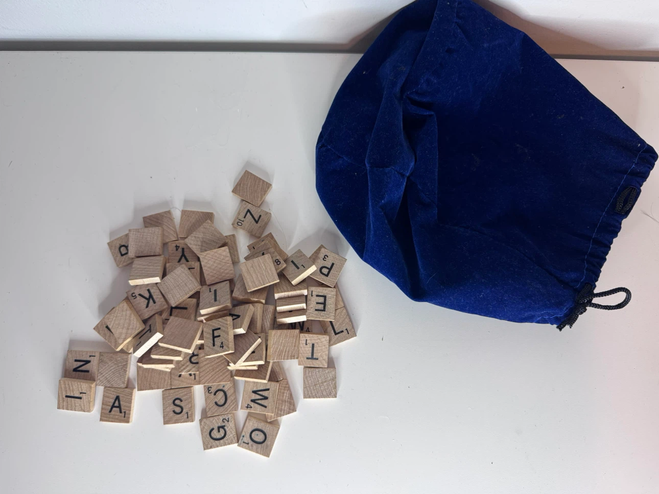 Wooden Scrabble letter tiles and blue velvet bag