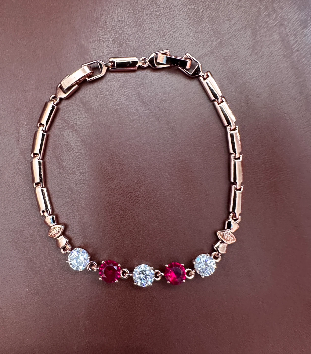 Rose gold tone link bracelet with red and clear crystals