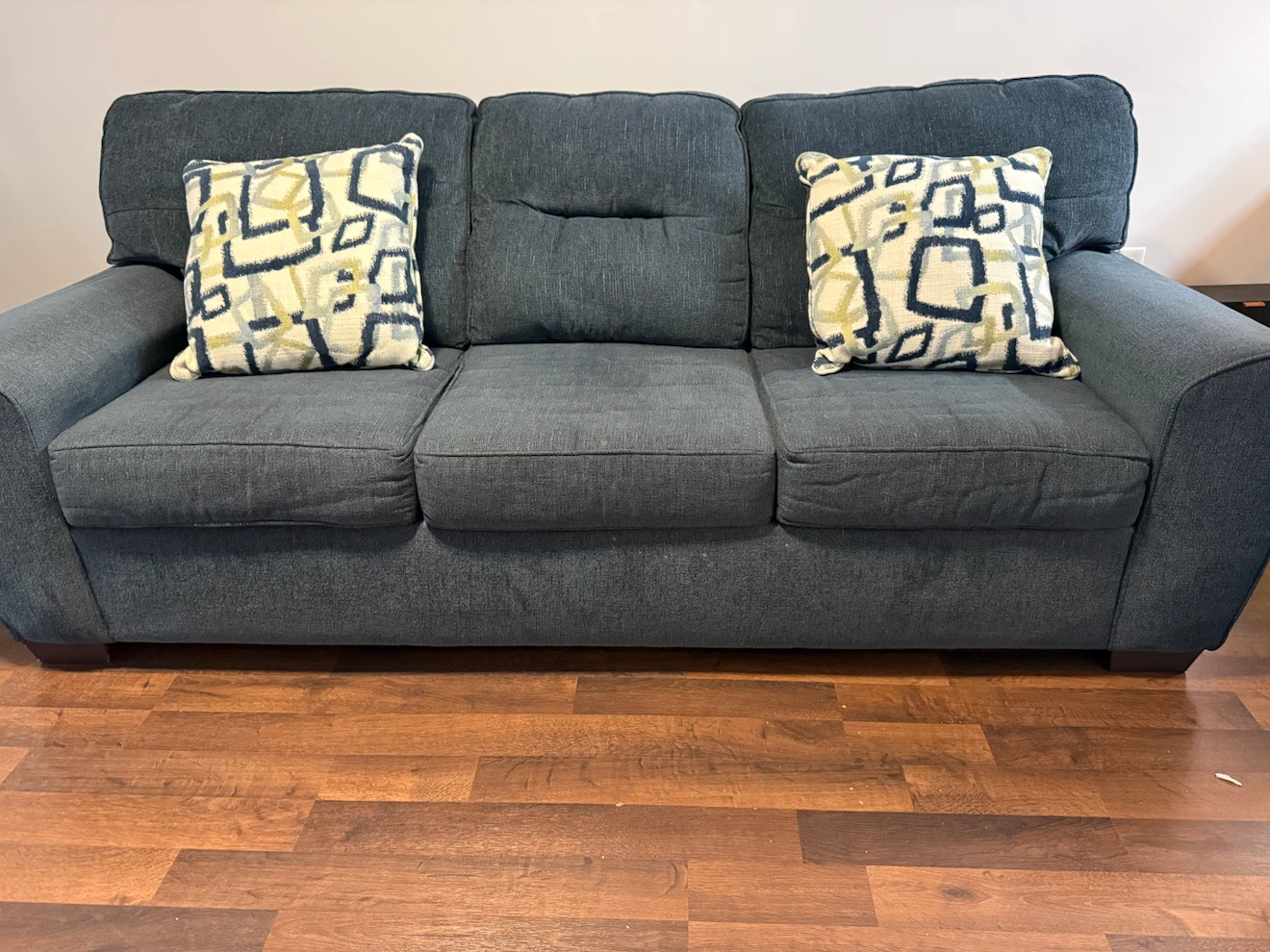 Grey three-seater sofa with accent pillows