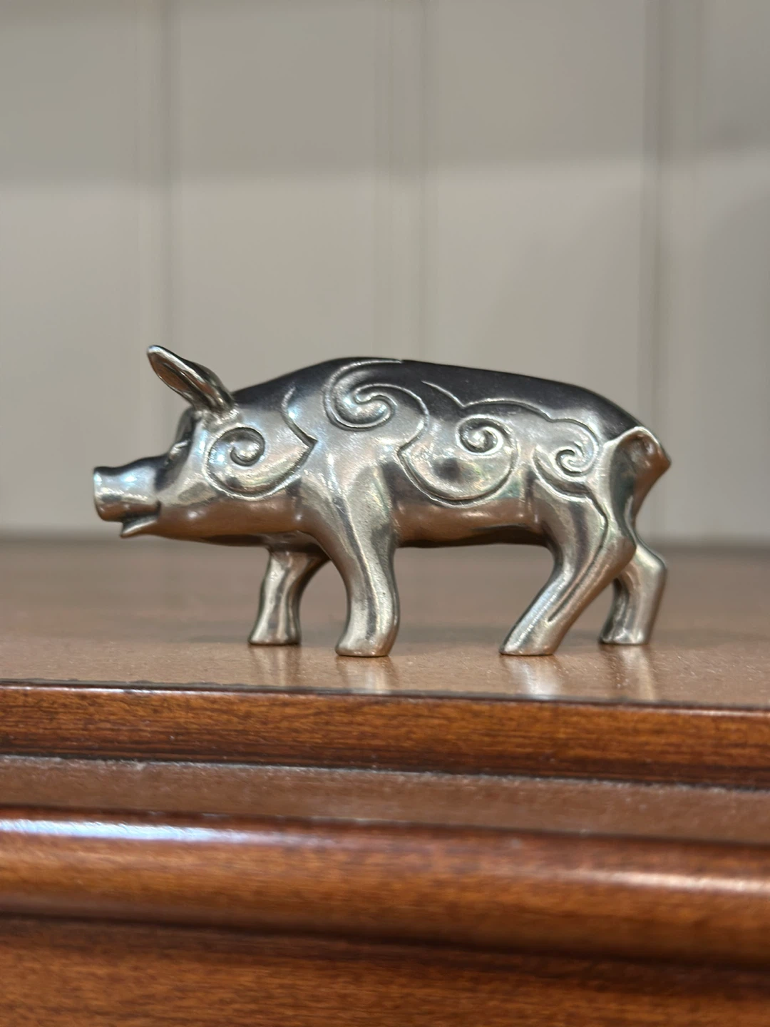 Small silver pig figurine with swirl patterns