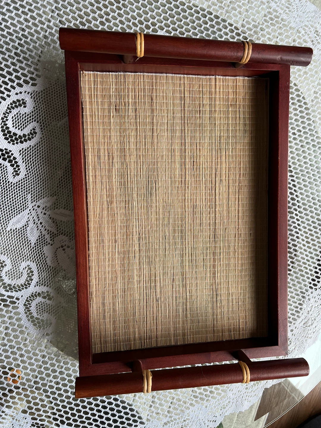 Reddish brown wooden tray with woven bamboo base