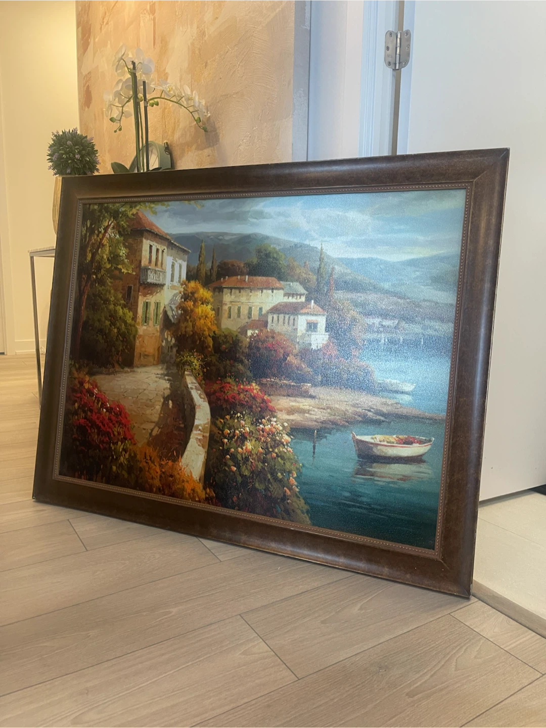 Large framed landscape painting of a coastal village