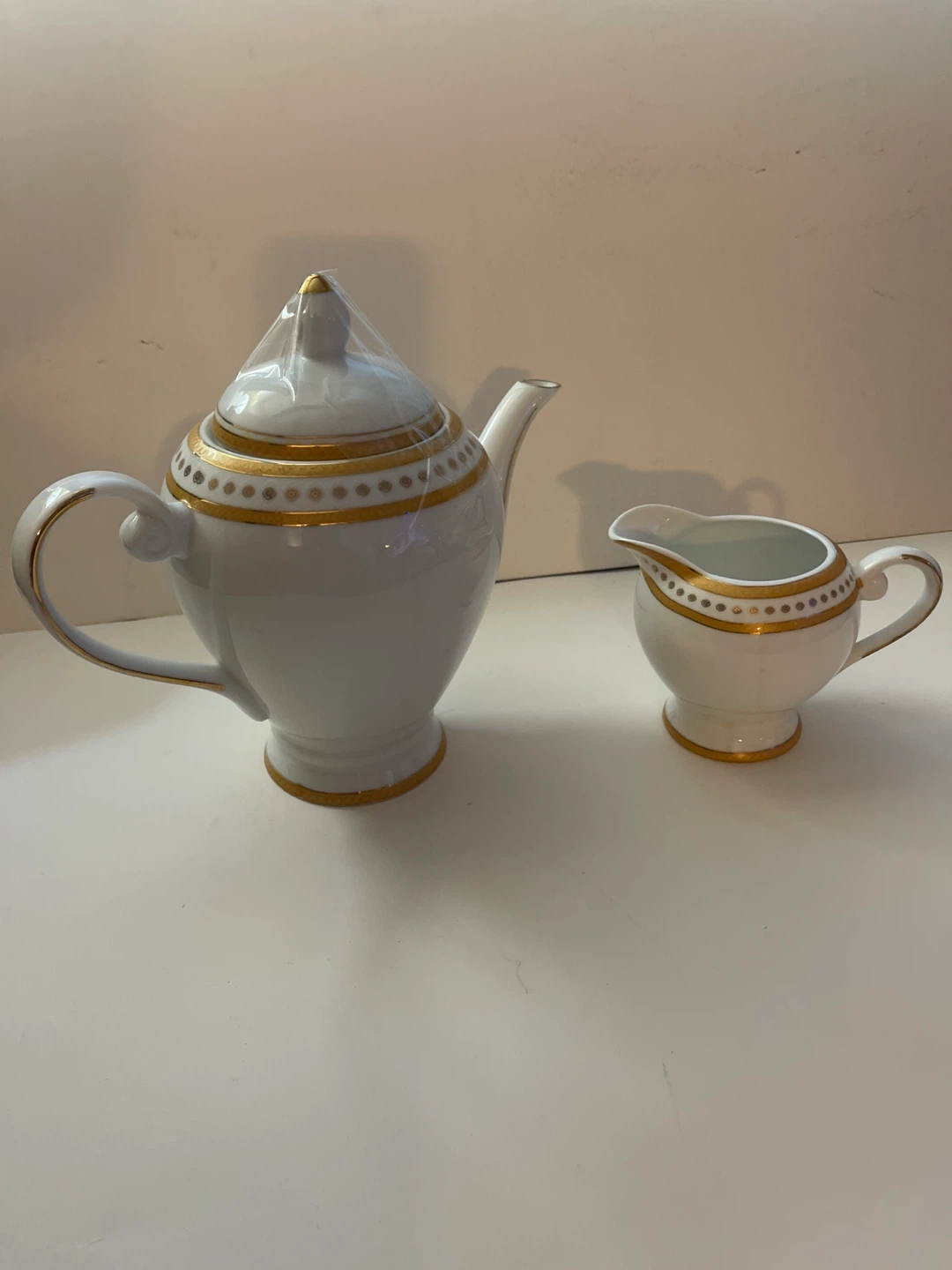 White and gold ceramic teapot and creamer set