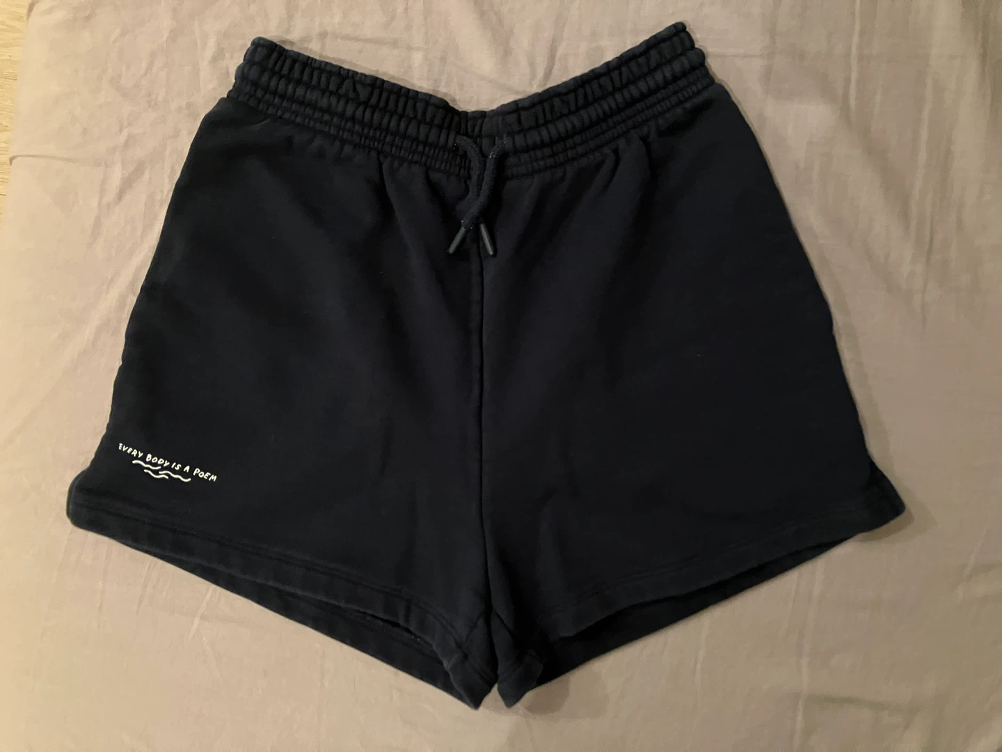 Navy shorts with "EVERY BODY IS A POEM" text