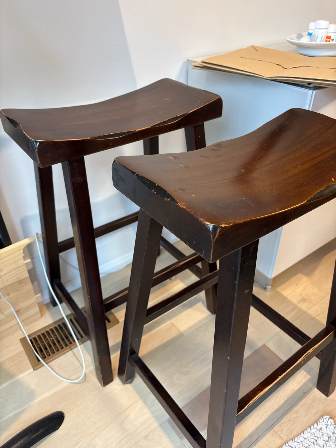 Two dark wood saddle bar stools