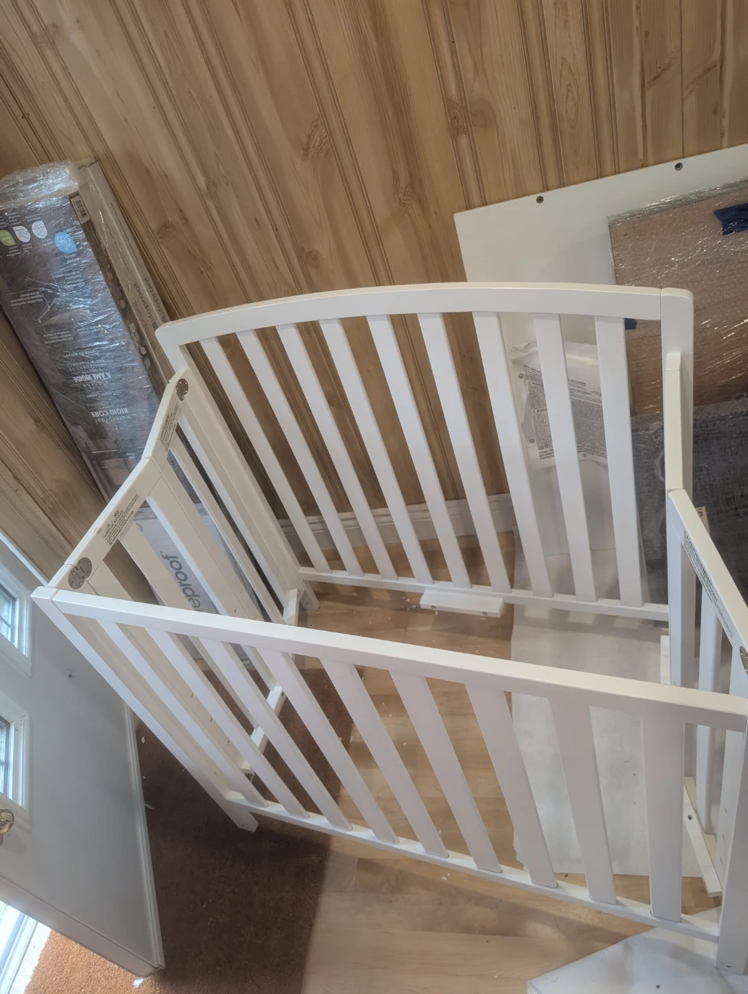 White wooden mini crib with mattress and unicorn sheet