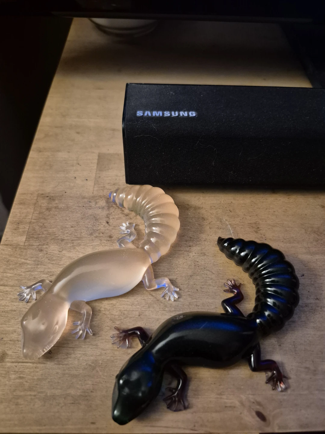 Two decorative resin geckos, opaque and black