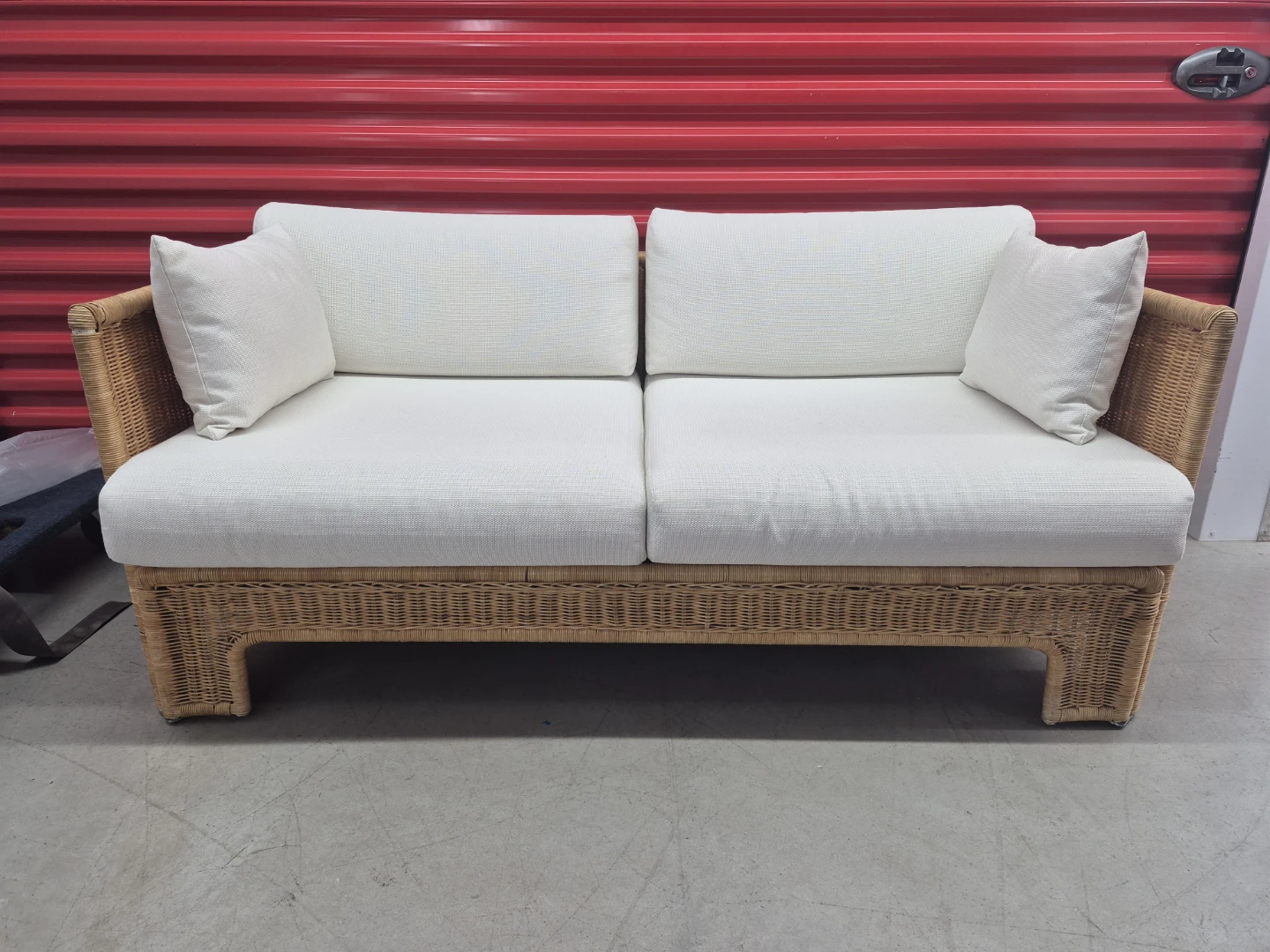 Woven wicker sofa with white cushions